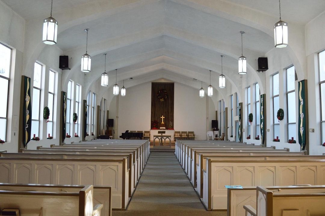 The sanctuary with wooden pews and a cross above the chancel